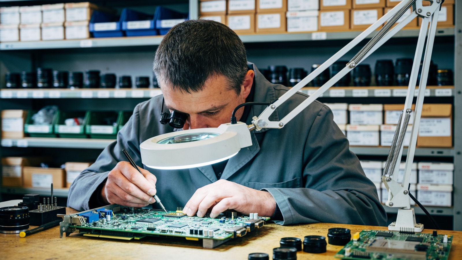 Prüfung einer Platine unter der Lupenlampe in einer Elektronikwerkstatt